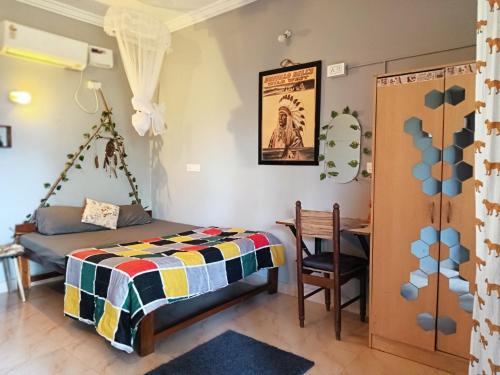 1 dormitorio con cama, escritorio y mesa en The Caveman Goa-River-view Retreat., en Arambol