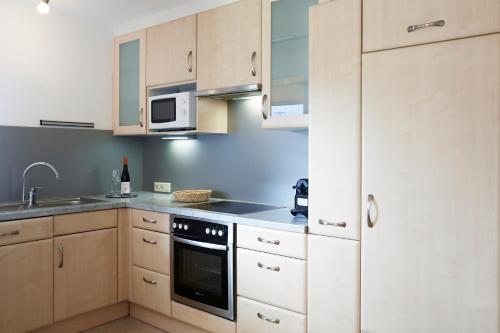 a kitchen with white cabinets and a sink and a microwave at Apartments Kirchebnerhof in Oetz