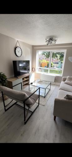 a living room with a couch and a table and a clock at DK House in Colchester