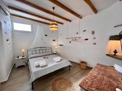 a bedroom with a large bed and a table at Dall'Egeo παραδοσιακό κυκλαδίτικο σπίτι in Vari