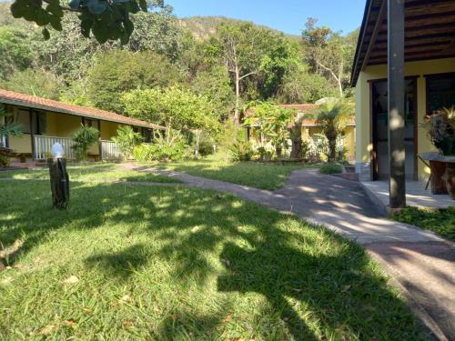 a yard in front of a house with a sidewalk at Embaúbas suíte privativa in Serra do Cipo