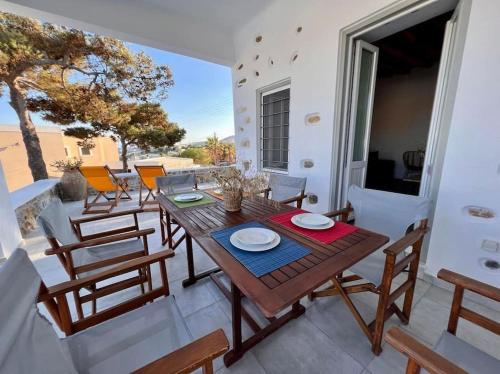 a wooden table and chairs on a patio with a view at Dall'Egeo παραδοσιακό κυκλαδίτικο σπίτι in Vari