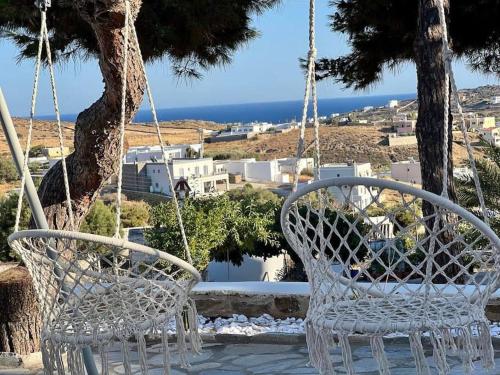 two white chairs hanging from a tree at Dall'Egeo παραδοσιακό κυκλαδίτικο σπίτι in Vari