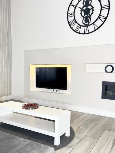 a living room with a white coffee table and a clock at Trigon Palace in Budapest