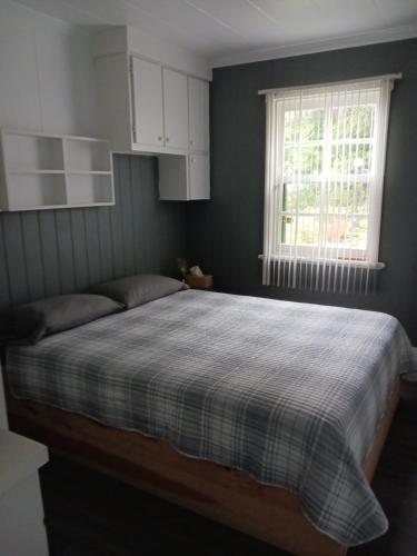 a bedroom with a bed with a checkered blanket at La Maison Vaillancourt in Saint-Laurent-de-l'ile d'Orleans