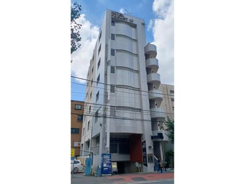 a tall white building on the side of a street at Nishikawaguchi Station Hotel - Vacation STAY 98562v in Kawaguchi