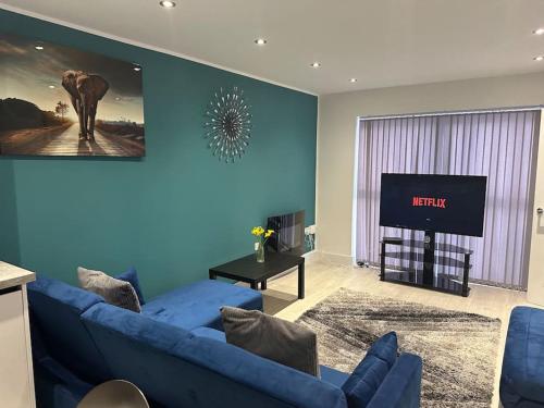 a living room with a blue couch and a tv at KYOTO HOUSE CENTRAL DERBY I 2 BEDROOMS, SPACIOUS, WARM & NEW with NETFLIX in Derby