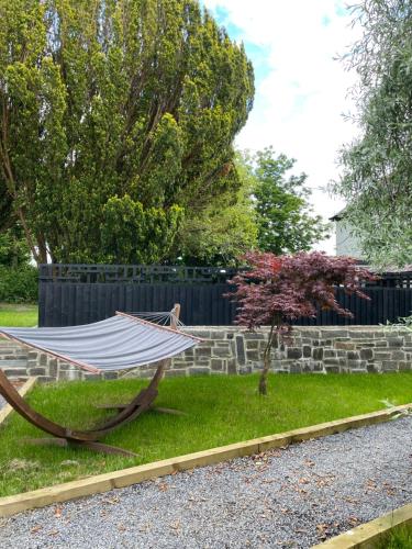 a hammock in a yard next to a stone wall at Garden Retreat Wales in Llandowror