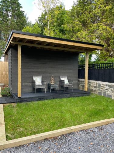 a pergola with two chairs and a grill in a yard at Garden Retreat Wales in Llandowror