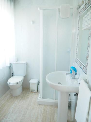 a white bathroom with a toilet and a sink at O Cunchal Rooms in Dena