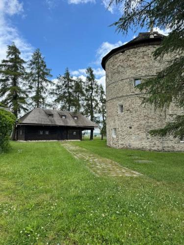 a stone building in a field next to a grass field at Dřevěnice in Němčice
