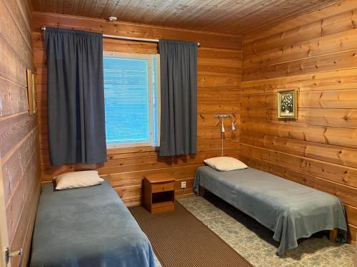 a bedroom with two beds in a log cabin at Taljatie Apartments in Rovaniemi