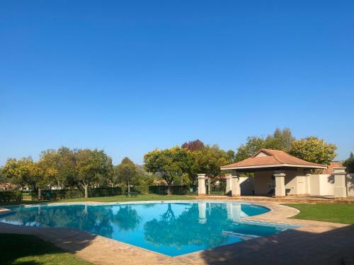 a swimming pool in a yard with a gazebo at Kingfisher House, Pecanwood Estate, Hartbeespoort in Hartbeespoort