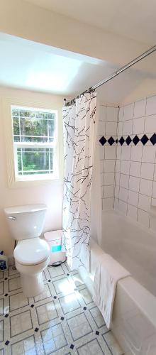 a white bathroom with a toilet and a shower at White House Tofino Downtown Villa in Tofino