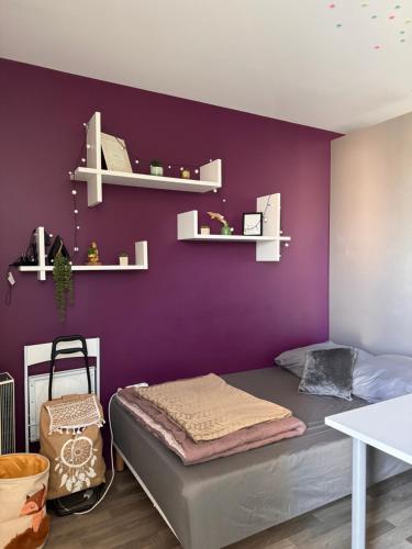 - une chambre dotée d'un mur violet avec un lit et des étagères dans l'établissement Studio urbain à 2 pas de Paris, à Nanterre