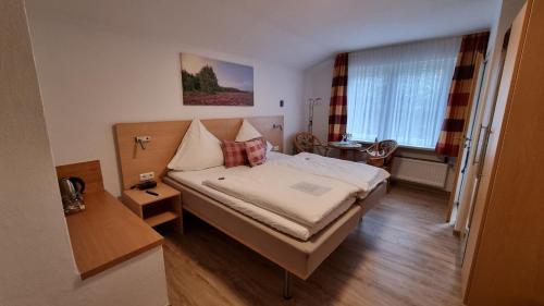 a bedroom with a bed and a table and a window at Café und Pension Höpen Idyll in Schneverdingen