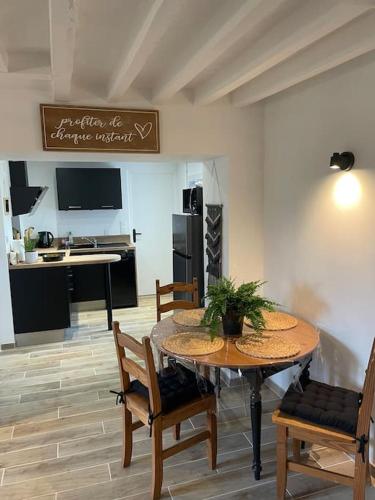 une salle à manger avec une table et des chaises et une cuisine dans l'établissement La maison de l'olivier, à Poses