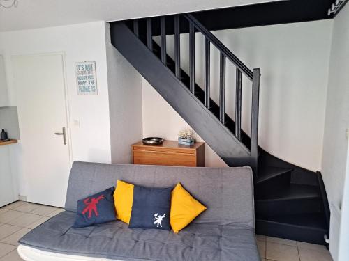 - un canapé avec des oreillers installé sous un escalier dans l'établissement Maison au calme, à Camiers