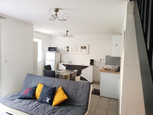 un salon avec un canapé et une cuisine dans l'établissement Maison au calme, à Camiers