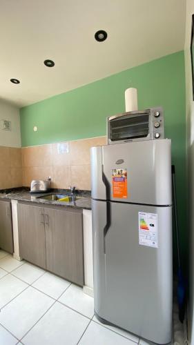 a kitchen with a refrigerator with a microwave on top of it at Departamentos Limay in Dina Huapi