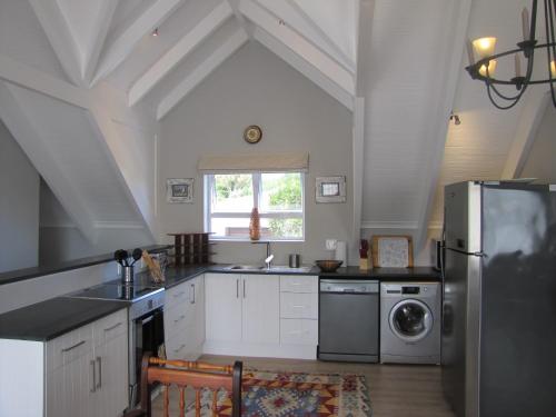 a kitchen with white cabinets and a stainless steel refrigerator at Holiday Home Our Happy Place in Plettenberg Bay