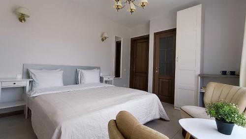 a bedroom with a white bed and a chair at "Trakaitis" apartments & holiday homes in Trakai