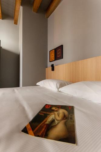 a magazine on a bed with a painting on it at Residenza San Longino in Mantova