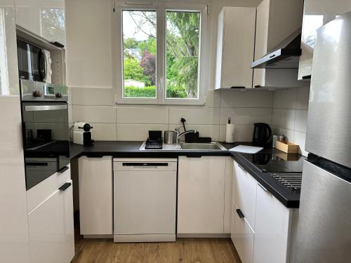 une cuisine avec des armoires blanches, un évier et une fenêtre dans l'établissement F3 verdoyant proche Paris Saclay, à Orsay