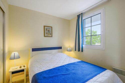 une chambre avec un lit bleu et une fenêtre dans l'établissement Résidence Port Bourgenay - maeva Home - Appartement 3 pièces 6 personnes Sélection MAE-2143, à Talmont-Saint-Hilaire