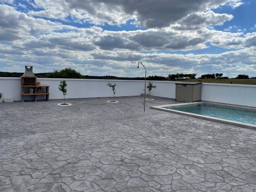 a patio with a swimming pool next to a white wall at Casa rural El Candil in Olivenza