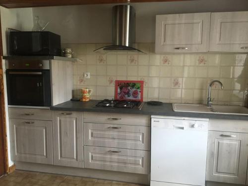 une cuisine avec des armoires blanches et un four à plaques de cuisson dans l'établissement Gîte à la ferme, à Rimont