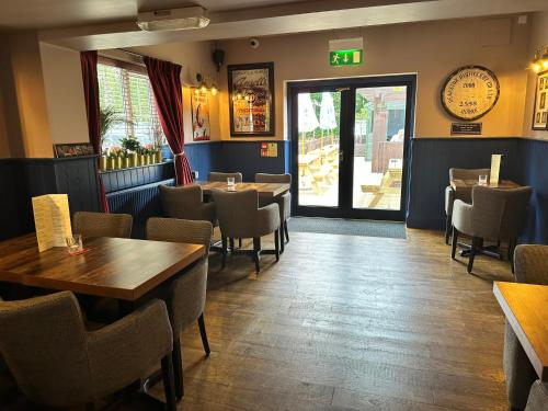 a restaurant with wooden tables and chairs and a door at The Prince Albert Pub & Hotel with onsite FREE PARKING 2 minutes from Legoland in Windsor
