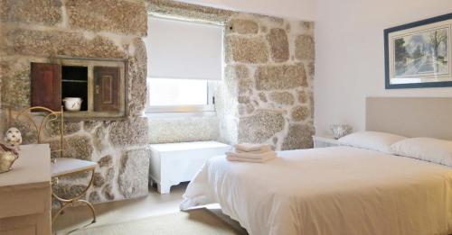 um quarto com uma cama e uma parede de pedra em Casa do O - Alojamento Local na Tbua
