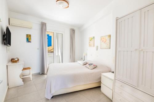 Dormitorio blanco con cama y armario en Mimis & Connie 1, en Karpathos