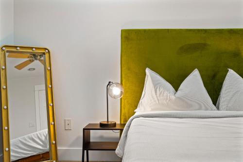a bed with a green headboard and a lamp on a table at Groovy SoCo Stay, Walk to Shops, Eats & Bars in Austin