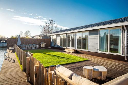 a house with a deck with a grass yard at Waterfront tiny home with spacious garden in Vinkeveen