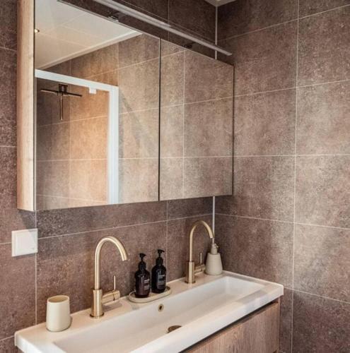 a bathroom sink with two faucets and a mirror at Waterfront tiny home with spacious garden in Vinkeveen