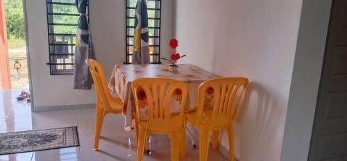 a dining room table with yellow chairs and a table and chairsktop at Cikra homestay in Batu Karang