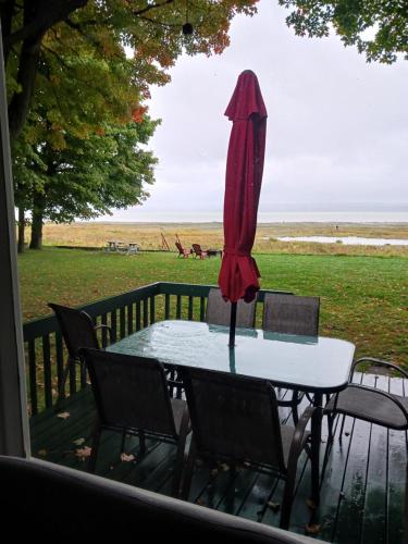 a table and chairs with a red umbrella on a deck at Maison Marcotte in Saint-Michel