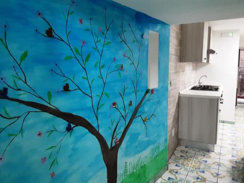 eine Küche mit einer blauen Wand mit einem Baumbild in der Unterkunft Dimora Maradona in Neapel