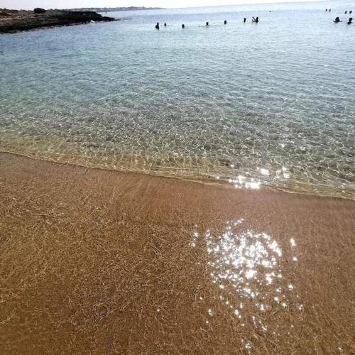 a group of people swimming in the water at the beach at casa al mare kalispera in Marina di Mancaversa
