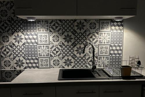 Il dispose d'une cuisine avec un évier et un mur carrelé. dans l'établissement Appartement jacuzzi maison spa, à Paris