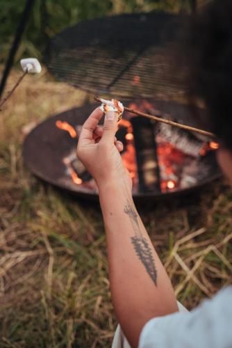 a person holding a piece of food in front of a grill at Kalmdown Cabin - Antwerp in Wuustwezel