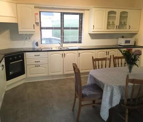 a kitchen with white cabinets and a table and a window at Entire home in Belmullet in Belmullet