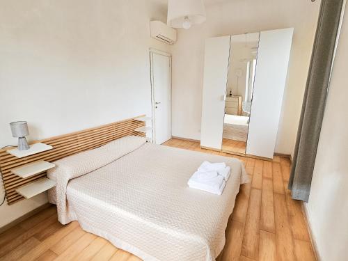 a white bedroom with a bed and a mirror at Narissara apartment in La Spezia