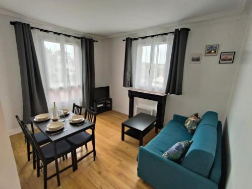 un salon avec un canapé bleu et une table dans l'établissement Appartement Entier, à Pierrefitte-sur-Seine