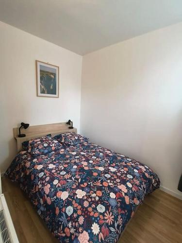 une chambre avec un lit avec une couette fleurie dans l'établissement Appartement Entier, à Pierrefitte-sur-Seine