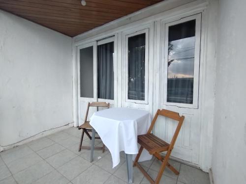 een witte tafel en stoelen op een veranda met ramen bij Pousada Jardins Campista in Macaé