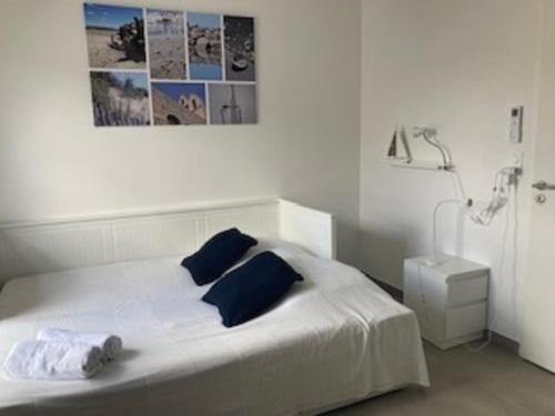 białe łóżko z niebieskimi poduszkami w sypialni w obiekcie Maison neuve clim 400m plage w Saintes-Maries-de-la-Mer