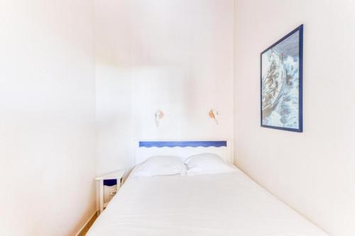 - un lit dans une chambre blanche avec une photo sur le mur dans l'établissement Résidence Port Bourgenay - maeva Home - Appartement 2 pièces 4 personnes avec balcon vue lac - Sélection - super Home MAE-2751, à Talmont-Saint-Hilaire